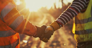 Two men shake hands on-site an unclear terrain